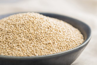 Blue ceramic bowl with raw white quinoa seeds on a gray concrete background and linen textile. Side