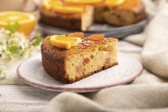 Orange cake and a cup of coffee on a white wooden background and linen textile. Side view, close