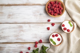 Yogurt with raspberry in clay cups on white wooden background and linen textile. top view, flat