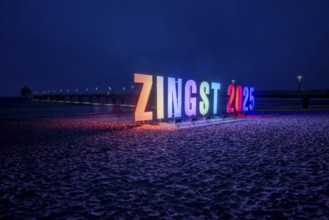 Colourful letters form the lettering Zingst 2025, with the pier of the Baltic seaside resort of