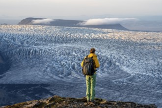 Young man, tourist in front of impressive glacier, in the evening light, glacier tongues