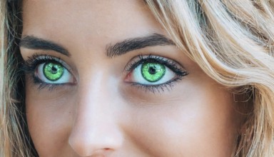 Intense close-up of a female face with green eyes and blonde hair, strong eye make-up, AI