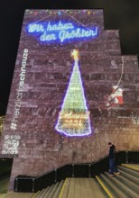 Digital projection of a Christmas tree on the gable wall of the City and State Library on the