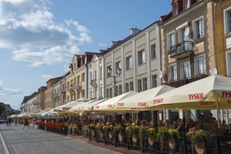 Lively street scene with restaurants and parasols in a historic old town centre in sunny weather,