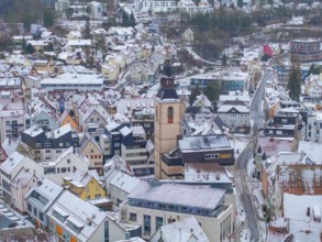 City panorama in winter with snow-covered roofs and central church tower in an urban setting,