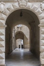 Narrow corridor with arches and stone walls, illuminated by ancient lanterns in a historic