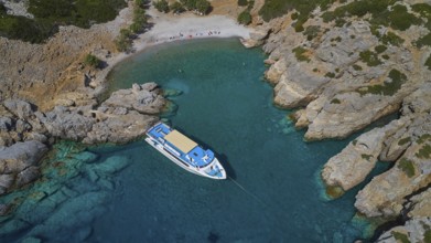 Palatia Beach, Palatia, A boat lies in a turquoise-blue, rocky bay with clear water and summer