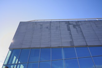 Modern building More og Romsdal Art Centre with glass front and reflecting blue sky, Molde,