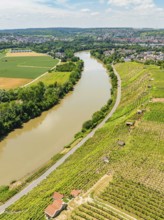 Wide green fields and a long river under a clear sky, seen from a hilly viewpoint, with a road