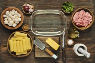 Fresh ingredients are arranged neatly on a wooden countertop in preparation for a pasta meal.