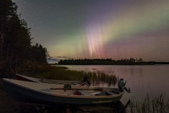 Aurora Borealis, northern lights or aurora borealis, lake with boats on the shore, Finland, Europe