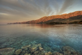 Morning light falls on a rocky coast with clear sea water, Mani peninsula, Peloponnese, Greece,