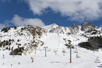 Skigebiet in Andorra mit mehreren Liften, Pisten und Skifahrern vor einer schneebedeckten