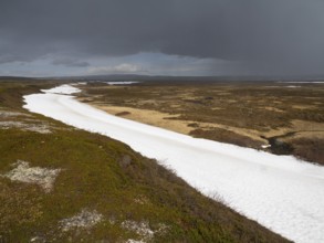 Rain clouds sweeping over tundra landscape, with snow remains in a small valley, Varanger National