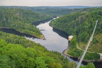 Panoramic view of a green landscape with a river winding through a densely wooded valley,