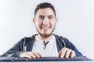 Portrait of nerdy man in front of keyboard. Smiling nerdy guy with hands on keyboard smiling at