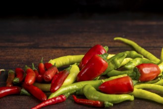 Green and red peppers scattered on a dark wooden surface, food photography