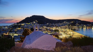 Agia Paraskevi Chapel, Illuminated coastal town at night with a view of the sea and hills in the