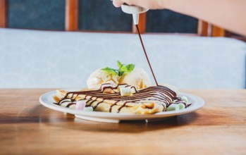 Chocolate crepe with ice cream on wooden background. Close up of sweet crepe with ice cream