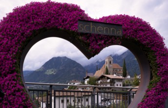 Photopoint, sign, flower heart, heart made of flowers, behind it the new parish church Maria