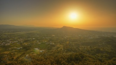 View from Filerimos hill in southwest direction, wide landscape with mountains at sunset in orange