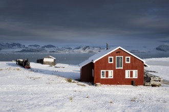 Historic mine railway and red house in front of the wintry, snow-covered Kongsfjorden, Ny-Ålesund,