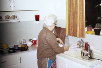 Ältere Frau an der Spüle zu Hause 1970er Jahre britische Lebensart