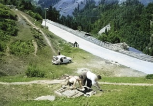 Men making tea and food, British Austin Cambridge A40 car in Austria, overland drive adventure