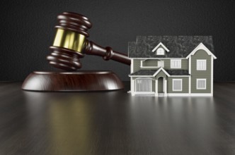 Wooden gavel and miniature house on a wood surface