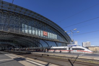 Central station with Deutsche Bahn AG logo, pillarless glass roof construction above the platforms.