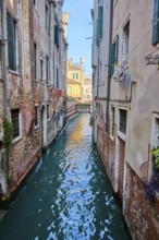 View on small bridge with the inscription 'Poste Vecie' going over a waterway in Venice on a sunny