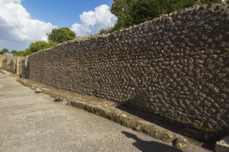 Long compacted crushed stone paved street with sidewalk and old stone walls plus residential