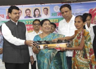 Maharashtra Chief Minister Devendra Fadnavis (L) distributes gas stoves to underpriviledged women