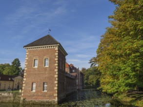 Historic brick building next to a river and autumn-coloured trees, velen, westphalia, germany