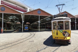 Historic yellow tram, Eléctrico, line 28 in front of tram depot and repair shop, Lisbon, Portugal,