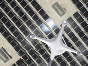 Overhead aerial view of a drone flying over an industrial warehouse roof covered in solar panels