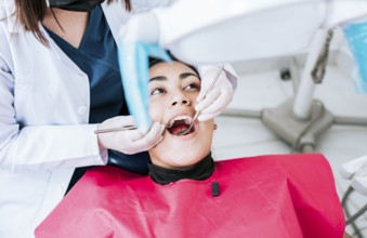 Top view of dentist doing cleaning to female patient lying down. Dentist doctor examining mouth to