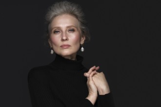 Portrait of a beautiful elderly woman in a white shirt with classic makeup and gray hair