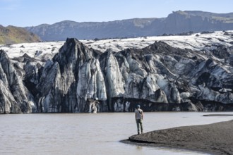 Tourist at the lakeside of a glacier lagoon, glacier tongue with crevasses and lake,