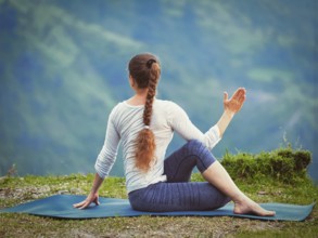 Hatha yoga outdoors, sporty fit woman doing yoga asana Parivrtta Marichyasana (or ardha