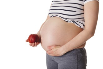 Healthy eating and diet during pregnancy concept, pregnant woman standing and holding red apple