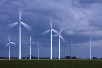 Spinning blades of wind turbines at the wind farm against stormy skies