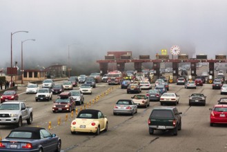 Cars driving on multi-lane approach to Golden Gate Bridge, road traffic, toll booth, fog, San