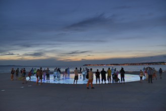 People at the Monument to the Sun, Pozdrav Suncu, by architect Nikole Bašica, at dusk, Zadar,