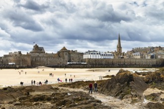 View of the city wall and cathedral from the Fort National, walkers on the beach, Saint-Malo,