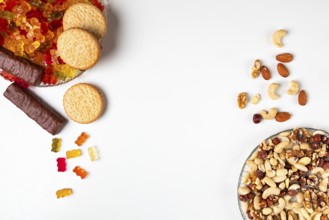 Comparison of unhealthy and healthy, various sweets and nuts, on plates, white background, copying