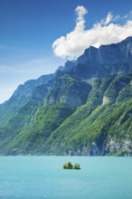 Sunny view over Lake Walen with the small chive island in the turquoise water and mountain range