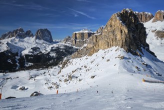 View of a ski resort piste with people skiing in Dolomites in Italy. Ski area Belvedere. Canazei,