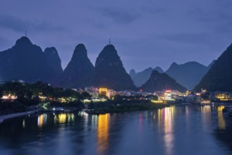 View of Yangshuo town illuminated in the evening with dramatic karst mountain landscape in