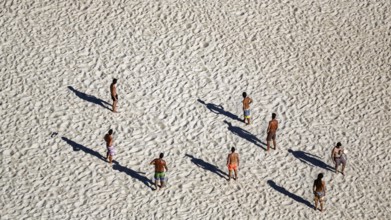 Beach volleyball on the beach of Nazaré, players cast long shadows, view from above, Portugal,